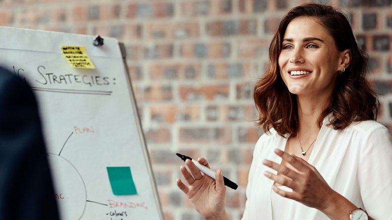 Beraterin erklärt an einem Whiteboard strategische Ansätze in einem Geschäftstermin.