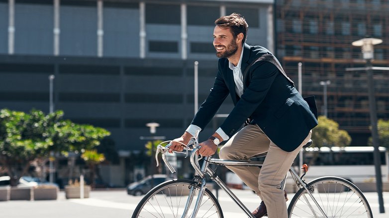Geschäftsmann fährt mit dem Fahrrad durch eine urbane Umgebung.